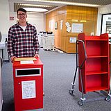 Eine Person steht hinter einer Zeitkapsel-Box 