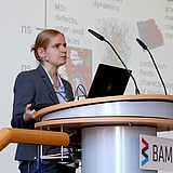 Eine Person steht an einem Rednerpult und hält eine Präsentation 