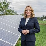 Eine Person steht neben einem Solarpanel 